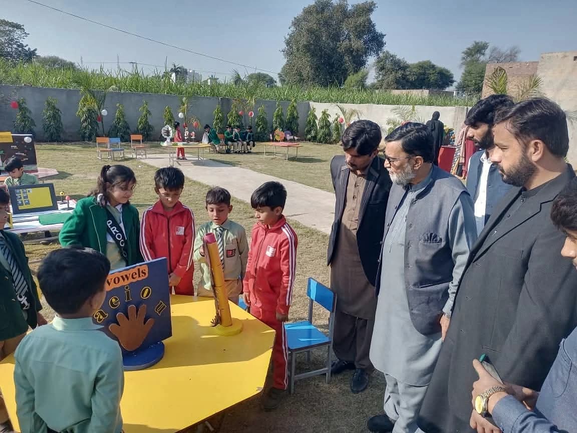 Children and adults gathered around tables outdoors.