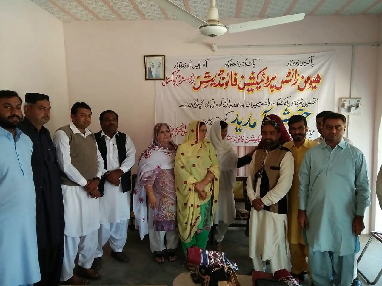 Women and men standing together at an indoor community gathering.