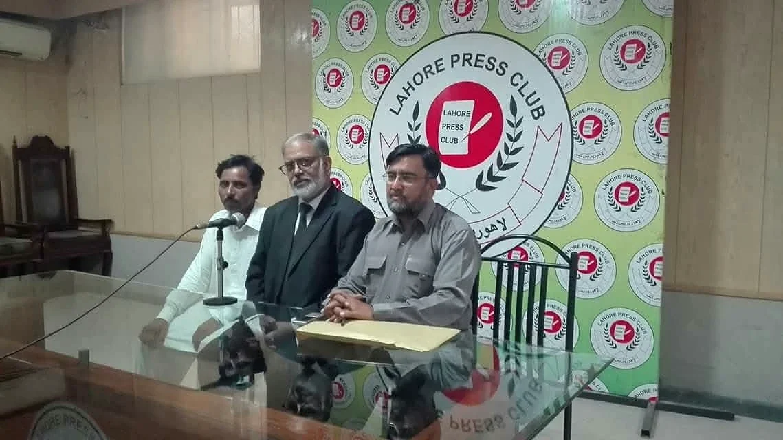 Three men standing in front of a Lahore Press Club banner.