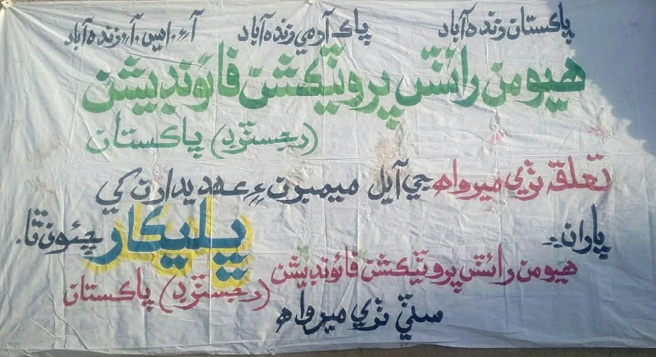 A photographed fabric banner with HRPF text and Urdu lettering.