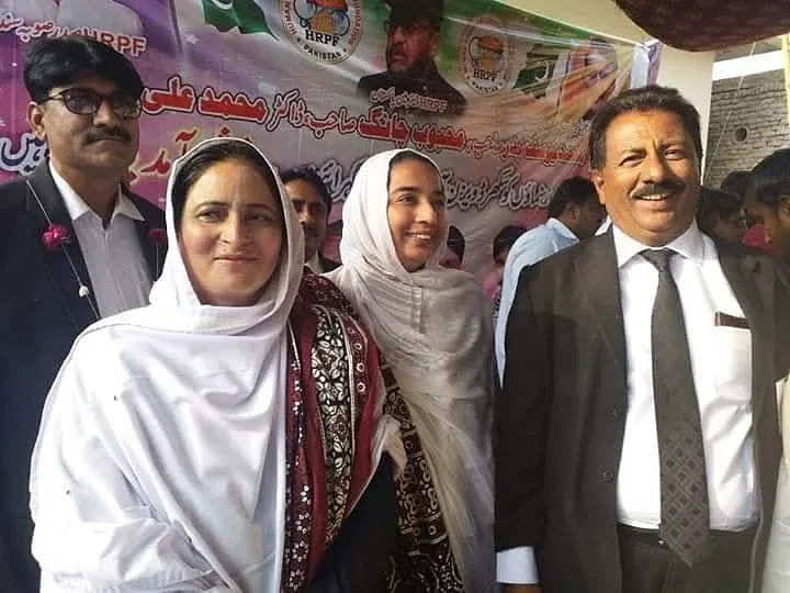 Two women and two men posing in front of a printed event backdrop.