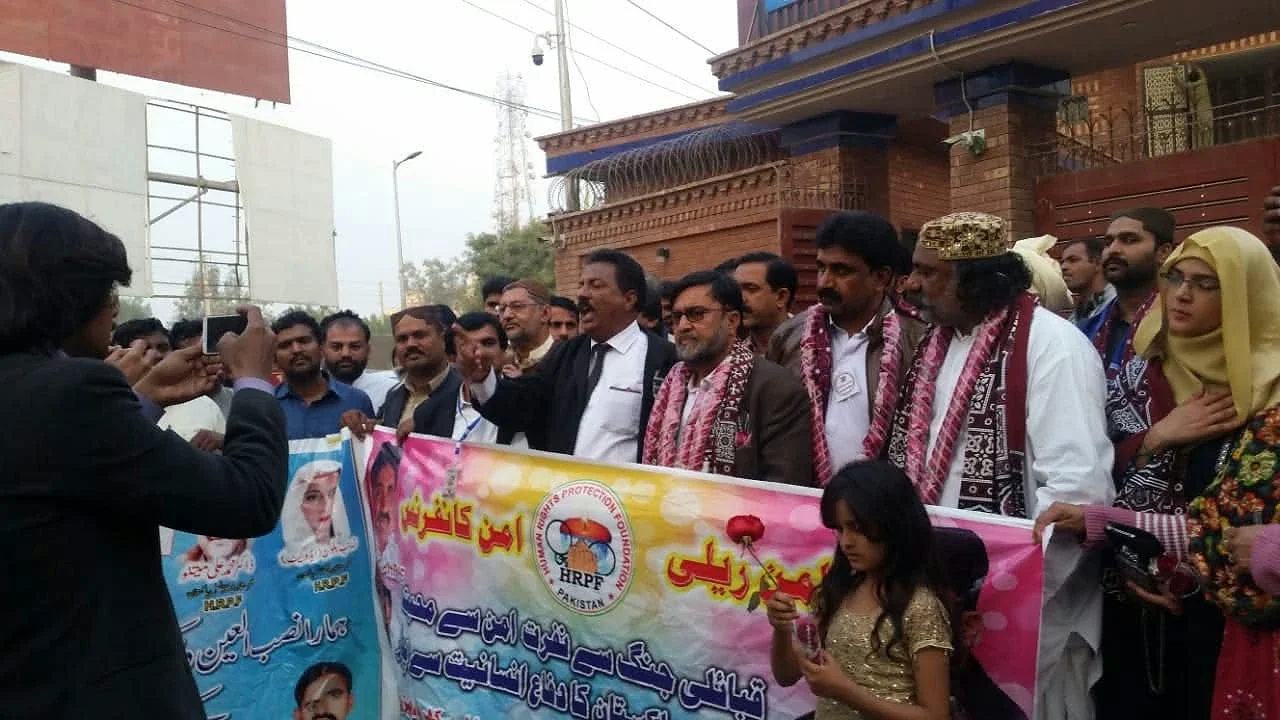 A group gathered outdoors holding a large printed banner.