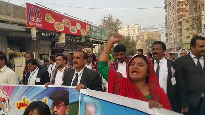 A woman raises her arm beside people holding a banner on a street.