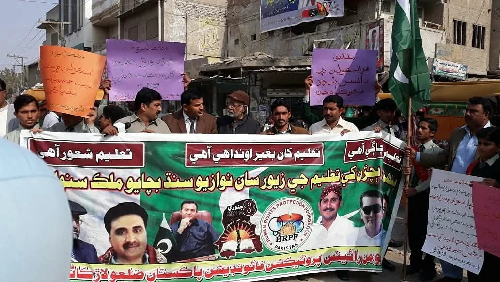 A group holding a banner and coloured placards in a street.