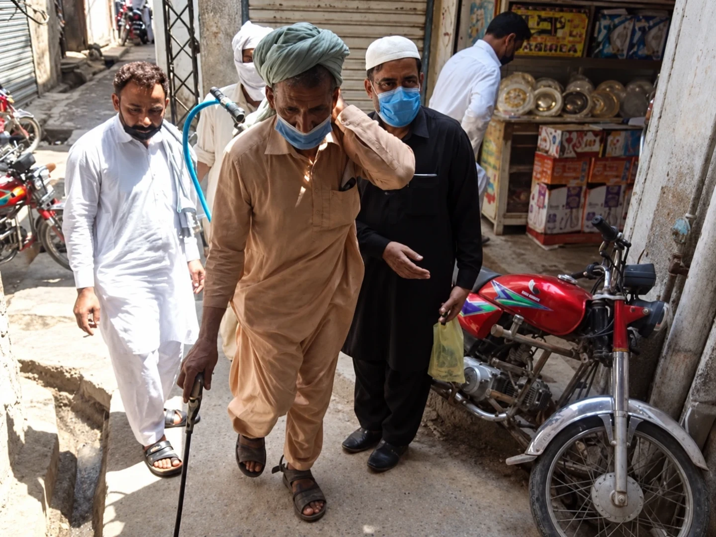 Men wearing face masks walking through a shopping street.