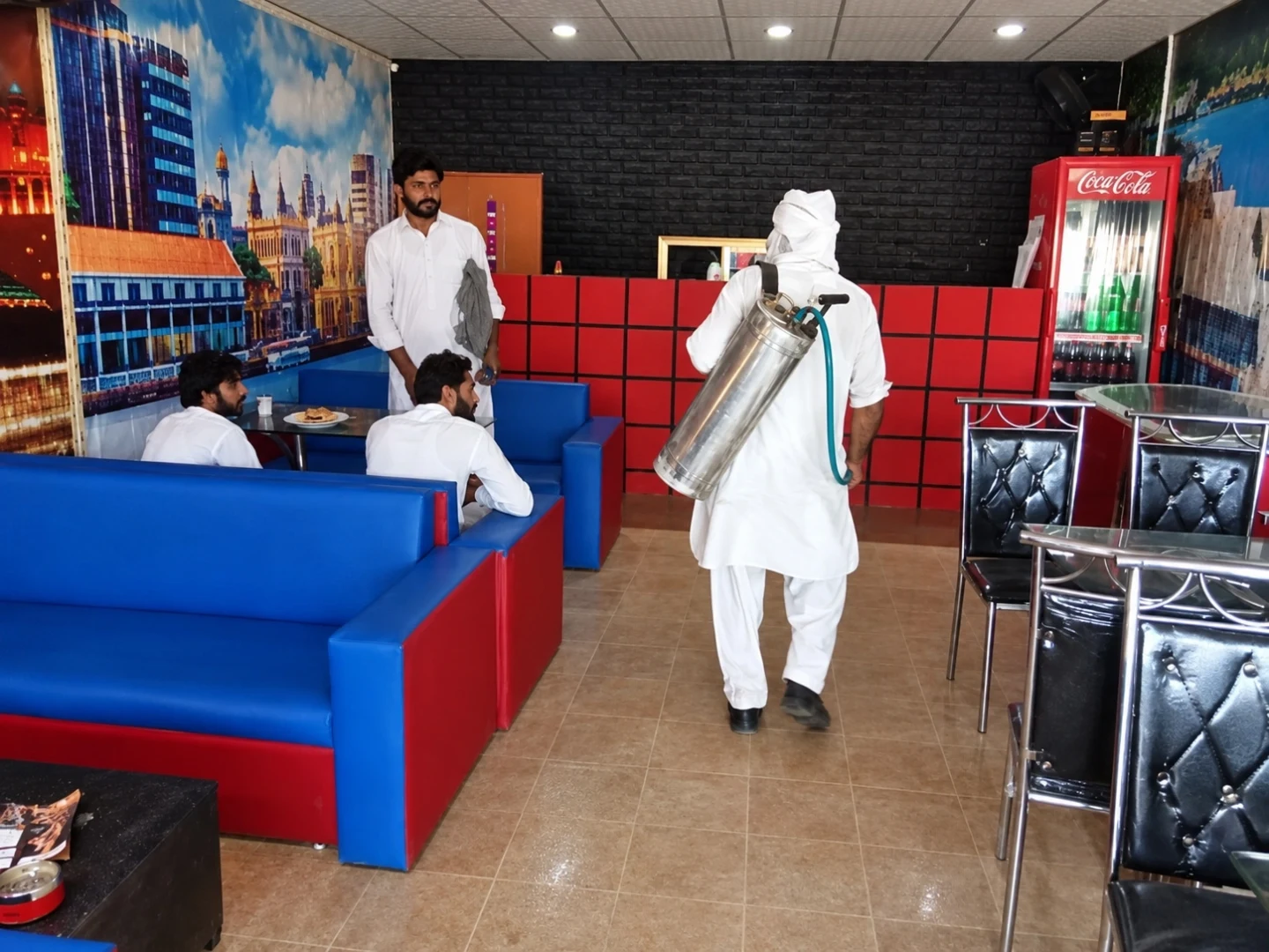 A person carrying a container inside a restaurant with blue and red seating.