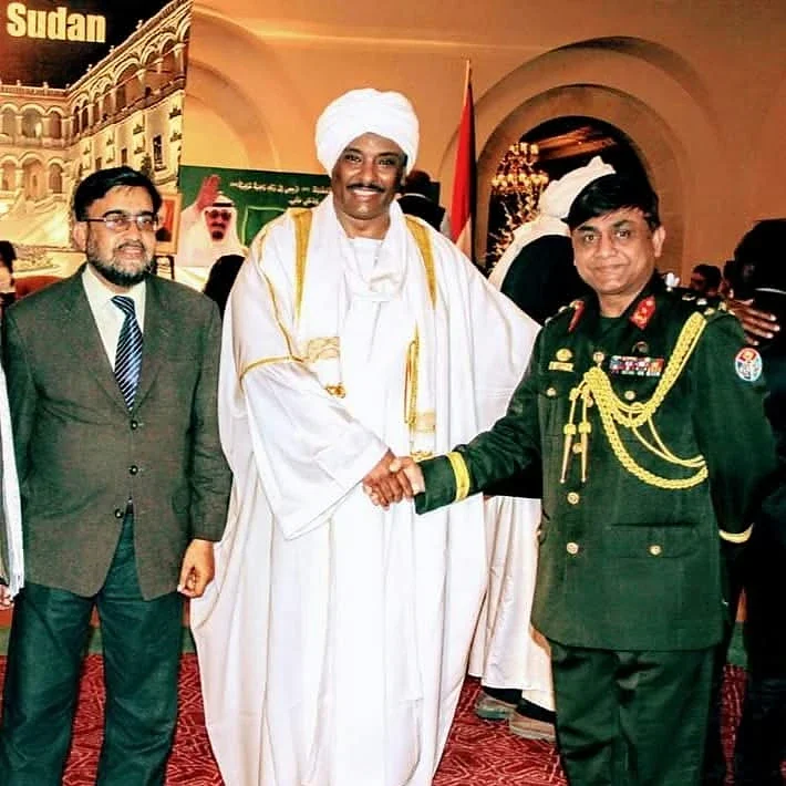 Three guests posing at a reception, including a person in ceremonial uniform.