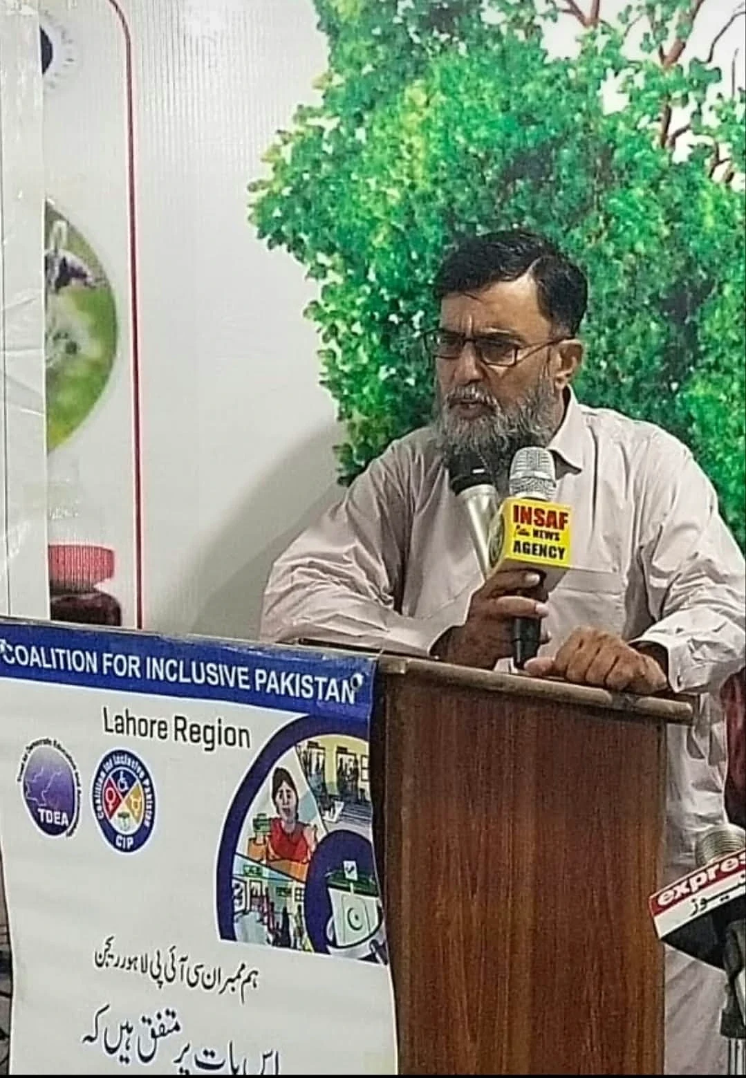 A man speaking into a microphone behind a wooden lectern.