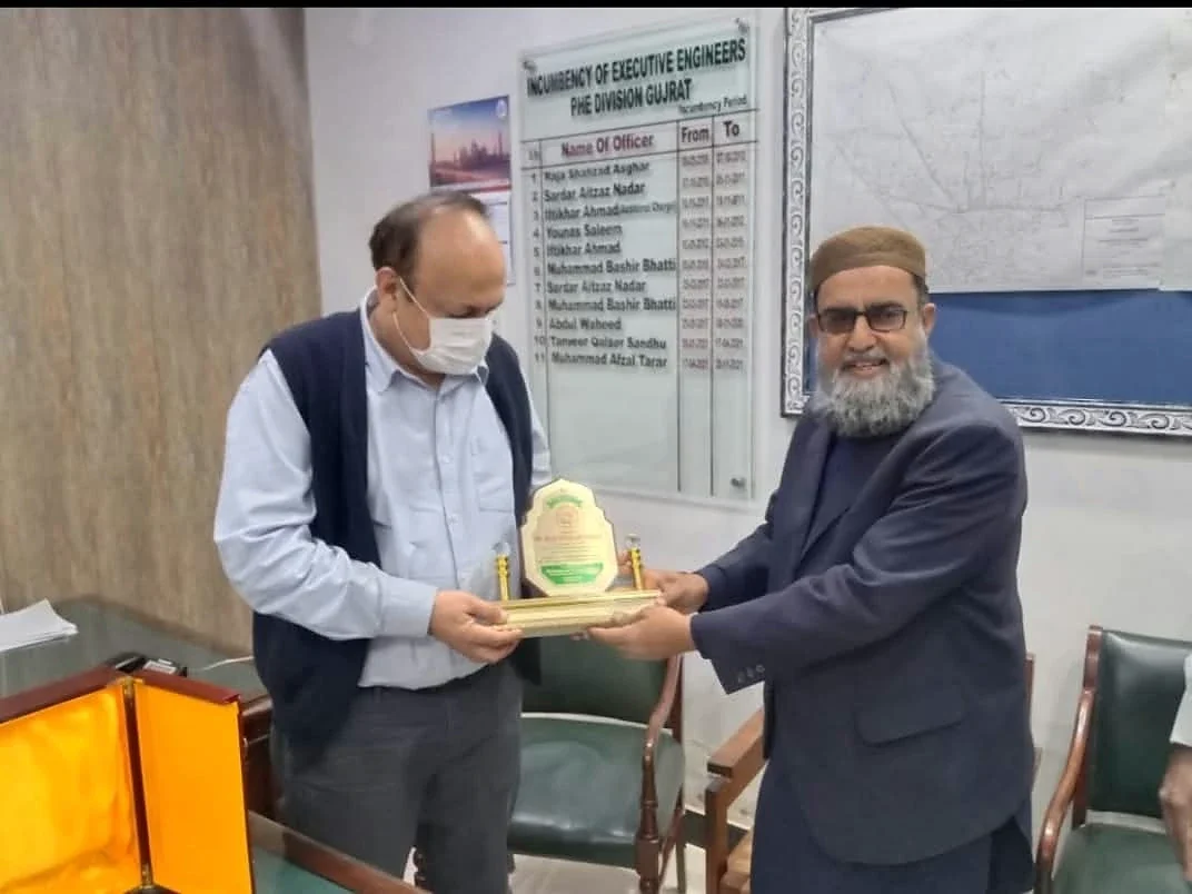 Two men holding a small presentation plaque in an office.