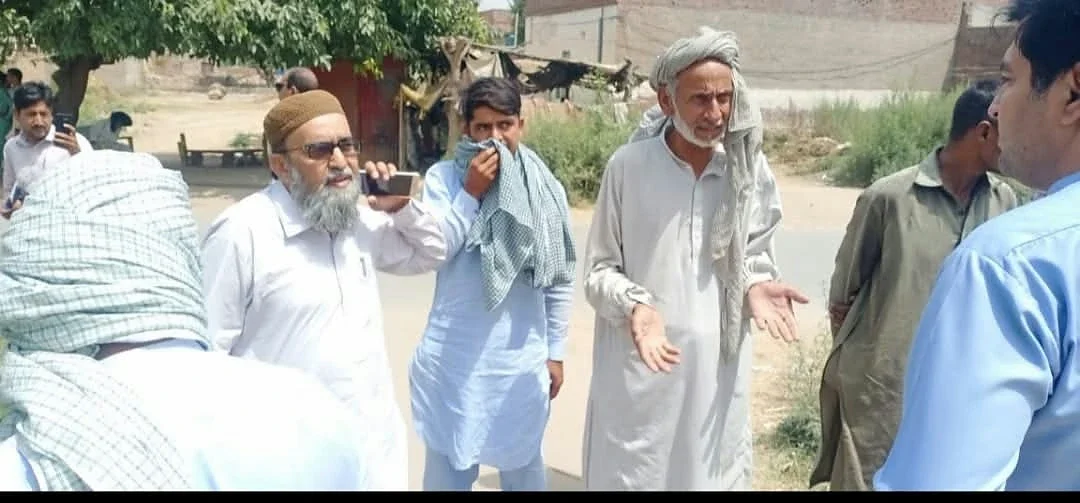 A group standing and talking outdoors beside a rural road.