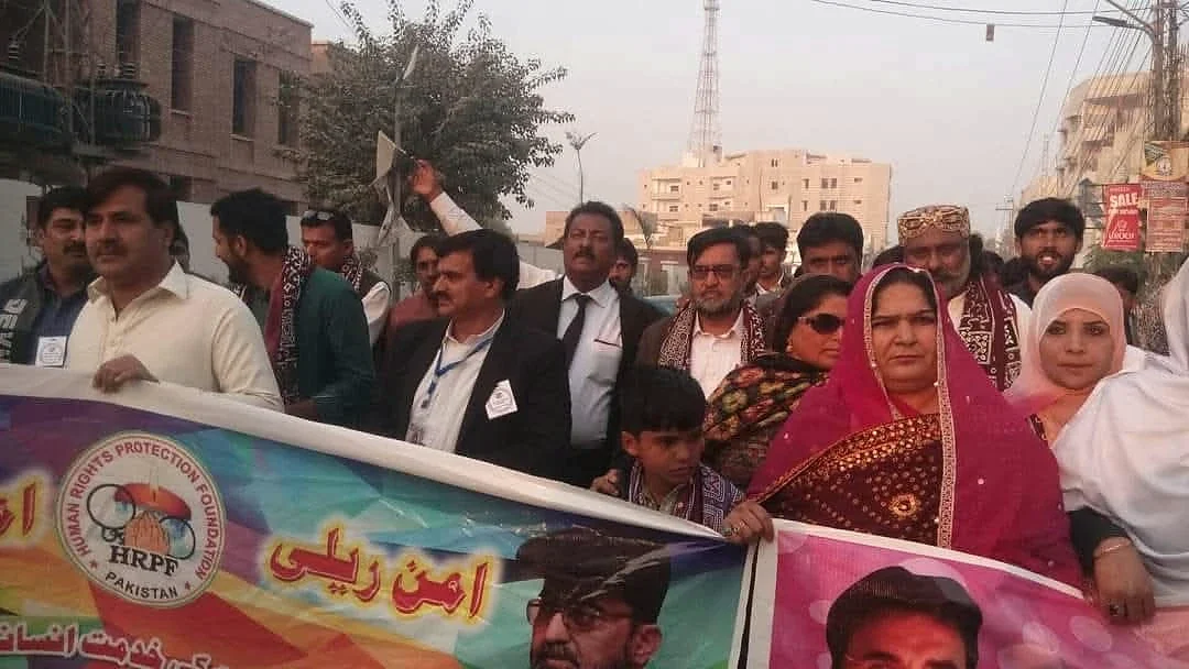 Women and men standing together outdoors behind a large HRPF banner.