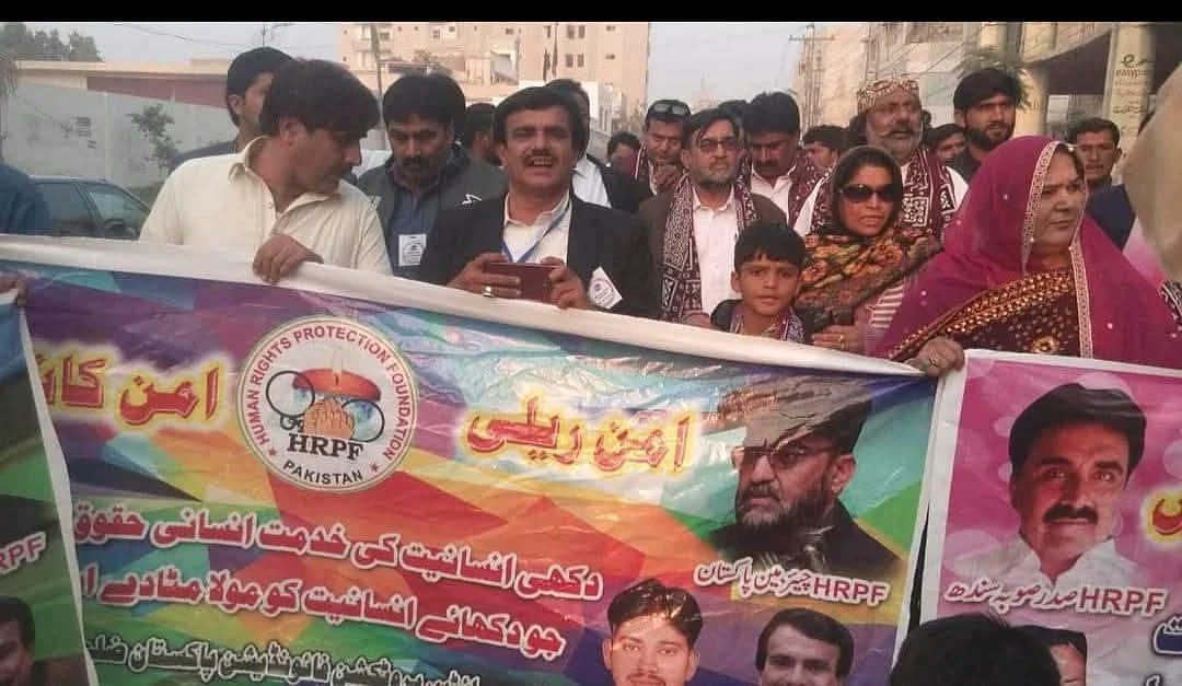 A group gathered outdoors with a large printed HRPF banner in the foreground.