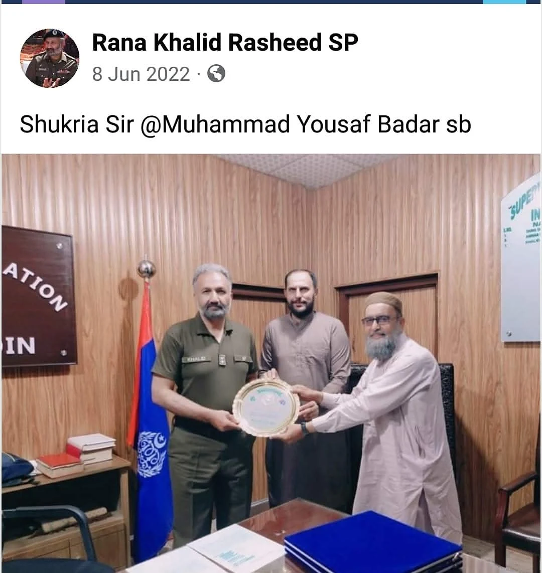 A social-media screenshot with text above a photograph of men presenting a plaque in an office.