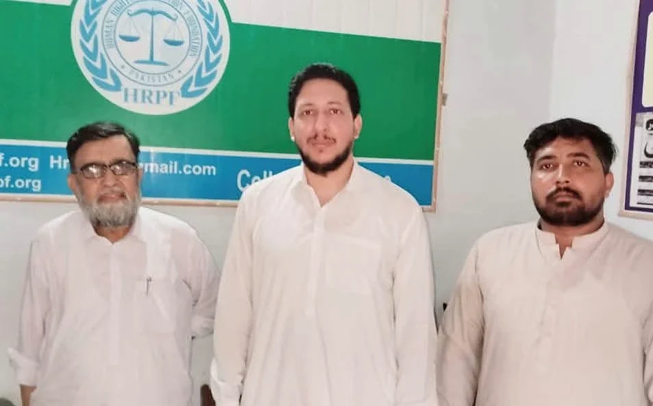 Three men posing indoors beneath a green HRPF logo backdrop.